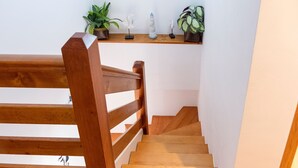 A wooden staircase with a handrail, leading to a landing with a shelf holding decorative items and plants. - Apartment in Sanxenxo near Lapa Beach (Sanxenxo)