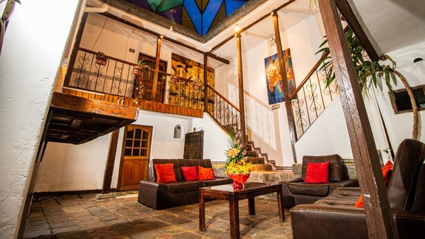 A spacious lobby with a high ceiling, a staircase, and a seating area with sofas and a coffee table. - Catama Inn Hotel (Cusco)