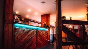 Zona de bar con paneles de madera y un letrero de neón.