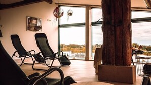 Una habitación con ventanas amplias, un tronco de madera y sillas negras.