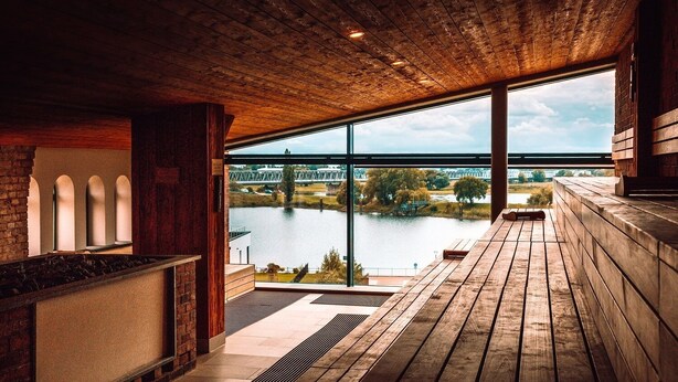 Una terraza de madera con vista a un río y un puente.