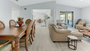 Amplia sala de estar con mesa de comedor, sofás y una cocina al fondo.
