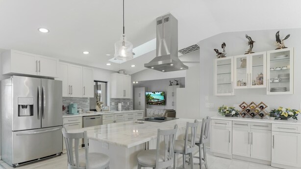 Una cocina moderna con una isla central, electrodomésticos de acero inoxidable y una campana extractora grande.