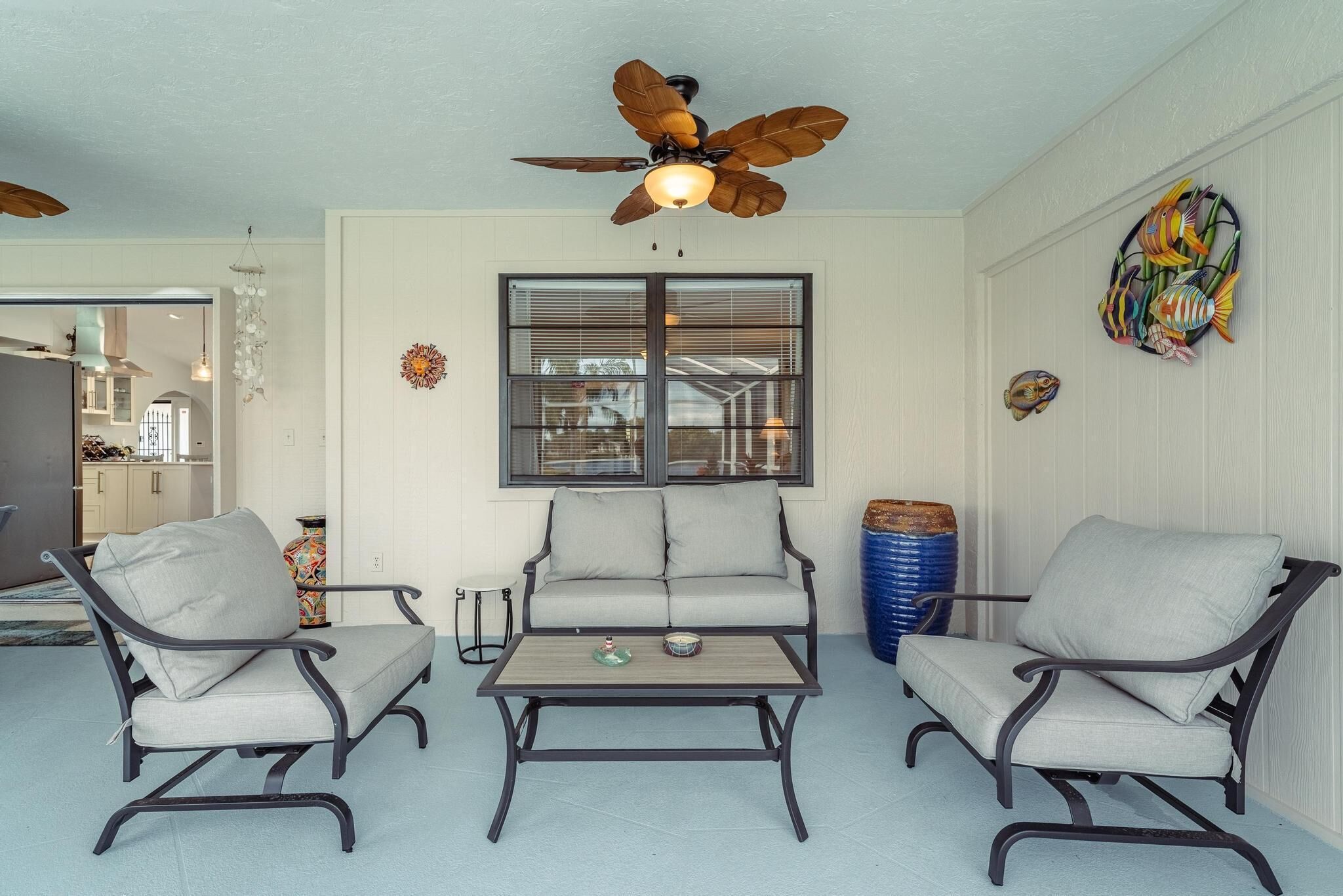 A room with a ceiling fan, a window with blinds, a sofa, two armchairs, and a coffee table.