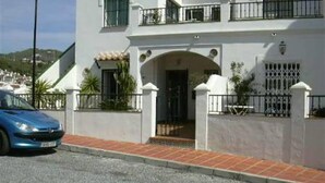 A two-story building with a white exterior, a gated entrance, and a blue car parked in front. - Villa "Casa Galesa" with Outdoor Pool (Nerja)