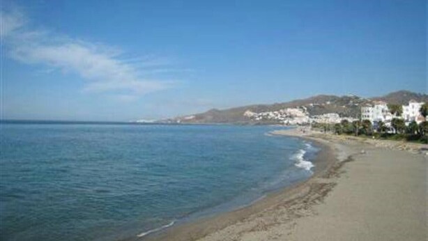 A beach with a clear sky, calm sea, and white buildings along the shore. - Villa "Casa Galesa" with Outdoor Pool (Nerja)