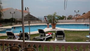 A pool area with lounge chairs, a thatched roof structure, and a view of the sea. - Villa "Casa Galesa" with Outdoor Pool (Nerja)