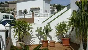 A terrace with potted plants, a white building, and a car. - Villa "Casa Galesa" with Outdoor Pool (Nerja)