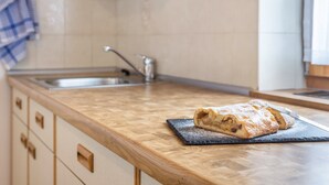 A kitchen with a wooden countertop, a sink, and a rolled pastry on a slate board. - Holiday Apartment 'Haus Thurn Apartment A' with Mountain View, Garden & Wi-Fi (Kastelruth)