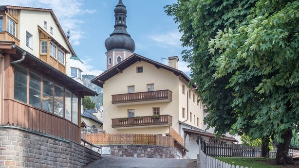 A two-story building with a balcony, a stone wall, and a wooden fence. - Holiday Apartment 'Haus Thurn Apartment A' with Mountain View, Garden & Wi-Fi (Kastelruth)