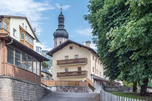 Un edificio de dos pisos con balcón, muro de piedra y cerca de madera.