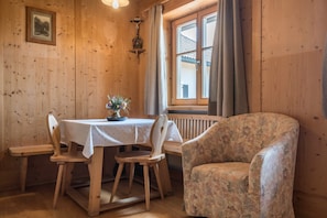 A wooden dining area with a table, chairs, and a floral-patterned armchair.