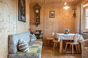 Ein Holzinnenraum mit einer Couch, einem Tisch mit Stühlen, einer Uhr und einer Nähmaschine.