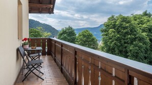 A balcony with a wooden railing, a table, and two chairs. - Holiday Apartment 'Haus Thurn Apartment A' with Mountain View, Garden & Wi-Fi (Kastelruth)