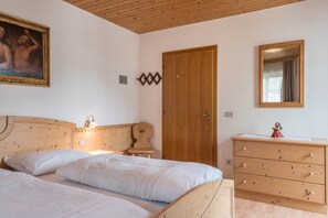 Ein Schlafzimmer mit einem hölzernen Bettgestell, einer Kommode aus Holz, einem Spiegel und einem Gemälde an der Wand.