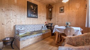 A wooden interior with a sofa, a dining table, a clock, and a painting on the wall. - Holiday Apartment 'Haus Thurn Apartment A' with Mountain View, Garden & Wi-Fi (Kastelruth)