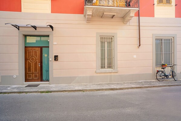 A building with a wooden door, a window, and a bicycle parked outside.