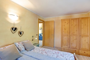 Une chambre à coucher comprenant un lit, une armoire et un luminaire fixé au mur.