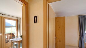 A room with wooden doors, a dining table with chairs, and a view through a window.