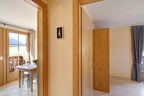 A room with wooden doors, a dining table with chairs, and a view through a window.
