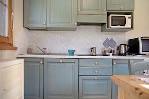Une cuisine avec des meubles de couleur turquoise, un four à micro-ondes, une machine à café et un grille-pain.