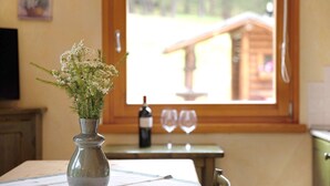 A dining table with a vase of flowers, a wine bottle, and two glasses.