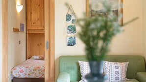 A room with a bed, a green sofa, a wall-mounted light, and a framed picture.