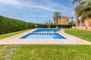 Une piscine rectangulaire à l’eau d’un bleu limpide, entourée d’une terrasse en béton.