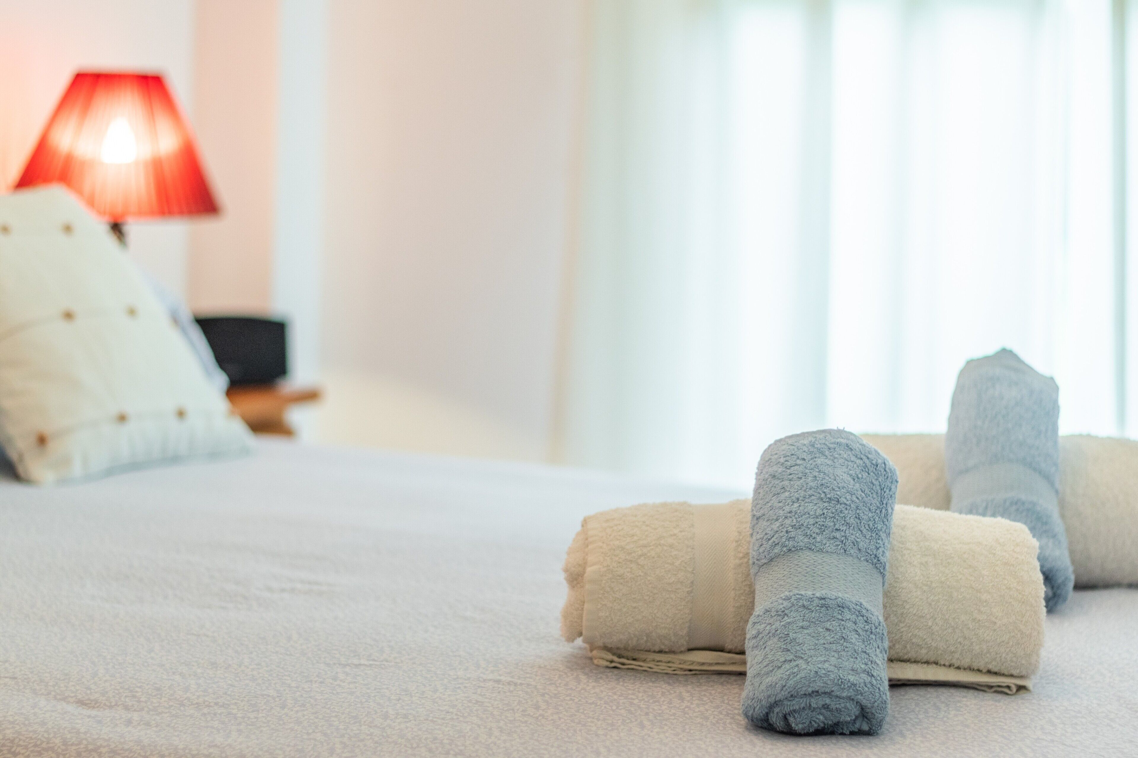 Un lit avec des serviettes soigneusement pliées et une lampe rouge en arrière-plan.