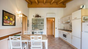 A kitchen with white cabinets, a wooden ceiling, and a dining area with white chairs and a table.