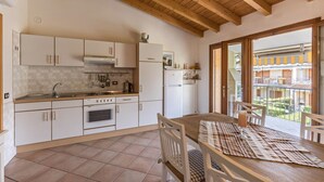 A kitchen with white cabinets, a wooden ceiling, and a dining area with a table and chairs.