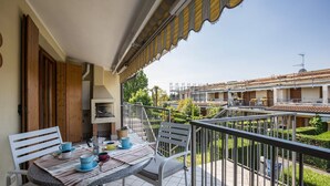 A balcony with a table and chairs, a view of neighboring buildings, and a clear sky.
