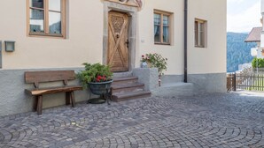 A building with a wooden door, a bench, and a potted plant. - Holiday Apartment 'Haus Thurn Apartment B' with Mountain View, Garden & Wi-Fi (Kastelruth)