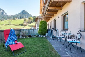 Een terras met tuinmeubilair, een tafeltje en uitzicht op een bergachtig landschap.
