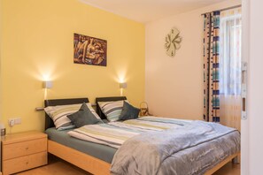 Een slaapkamer met een bed, nachtlampjes, een klok, een schilderij en een gordijn.
