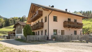Un bâtiment à deux étages doté de balcons en bois, d’une allée bordée d’une clôture et situé dans un cadre rural.