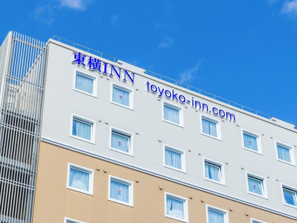Un edificio de varios pisos con un letrero que dice "TOYOKO INN" y la página web "toyoko-inn.com".