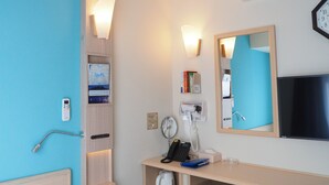 A hotel room with a bed, a bedside table with a phone, a mirror, a shelf with books, and a wall-mounted air conditioner. - Toyoko Inn Yokohama Shiei-chikatetsu Center Minami-eki (Yokohama)