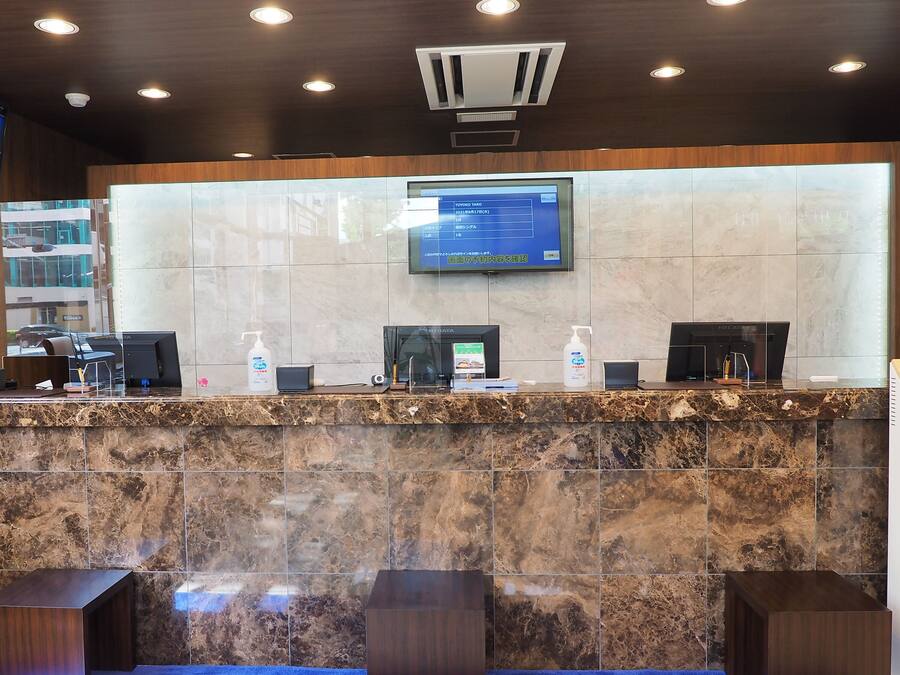 A reception desk with a digital screen, a marble counter, and a wooden panel.