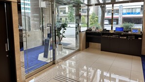 A modern reception area with a glass door, a reception desk, and a blue carpet. - Toyoko Inn Yokohama Shiei-chikatetsu Center Minami-eki (Yokohama)