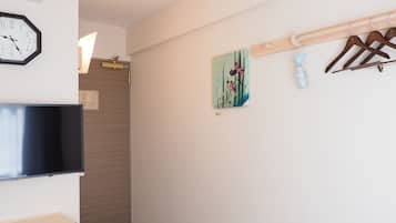 A hallway with a clock, a painting, and a coat rack.
