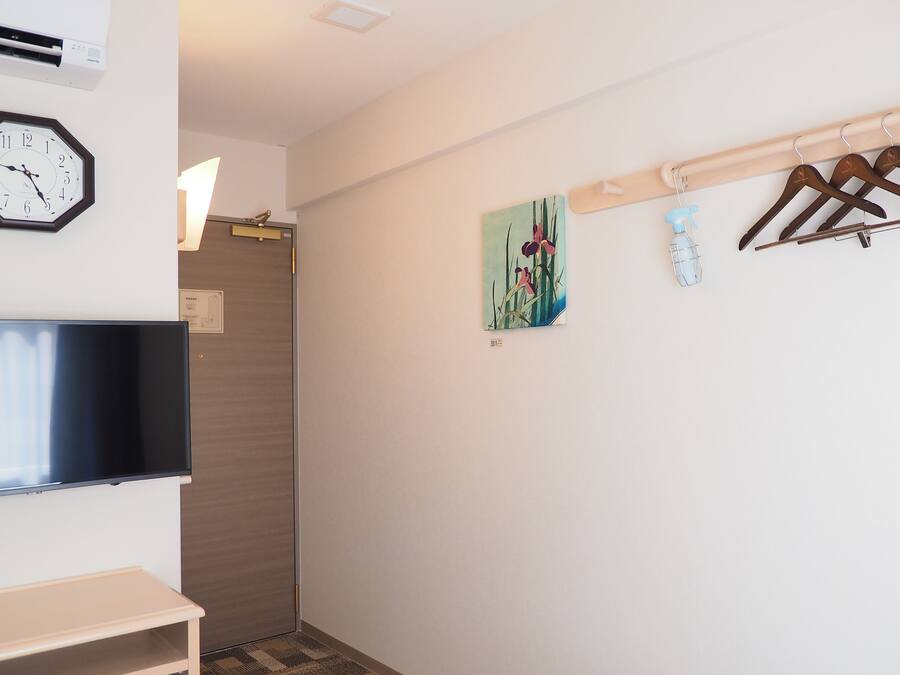 A hallway with a clock, a painting, and a coat rack.