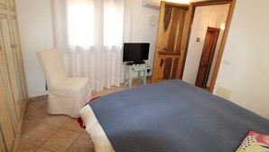 Een slaapkamer met een bed, een stoel, een televisie en een deur.