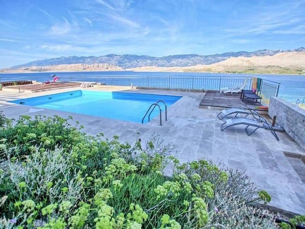 A swimming pool with a view of the ocean and mountains in the background.