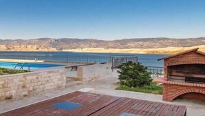 Una piscina con vistas a un paisaje desértico, una terraza de madera y una zona de barbacoa de ladrillo.