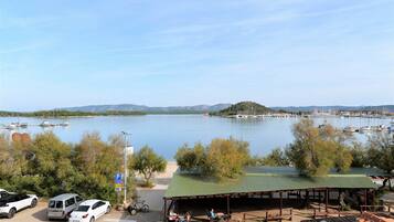 A lakeside view with boats, a covered seating area, and parked cars.