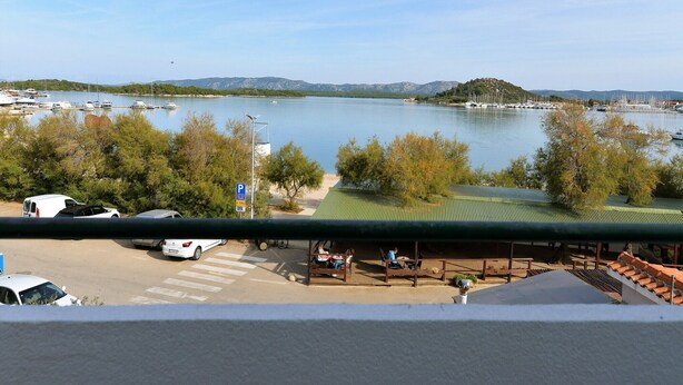 Una marina con barcos, un estacionamiento y vistas a un lago con montañas al fondo.