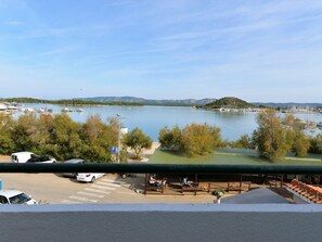 Una marina con barcos, un estacionamiento y vistas a un lago con montañas al fondo.