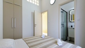 Habitación de hotel con cama, armario, baño con espejo y ventana.