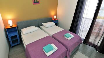Quarto de hotel com duas camas, uma mesa de cabeceira com abajur e um quadro na parede.